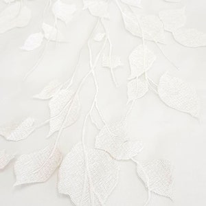 Puede incluir: Tela blanca transparente con un patr&oacute;n floral bordado. La tela tiene una sensaci&oacute;n delicada y aireada, perfecta para crear prendas o decoraci&oacute;n del hogar.