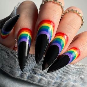 May include: Close-up of a hand with five long, black, almond-shaped nails. Each nail is painted with a rainbow design featuring alternating stripes of red, orange, yellow, green, blue, indigo, and violet.