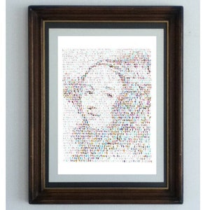 May include: A framed portrait composed of a mosaic of colourful letters and numbers. The dark brown frame surrounds a white mount, enhancing the artwork's visual impact. The portrait is a unique piece of art, suitable for home decor.