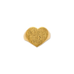 May include: A gold heart-shaped ring with a textured surface.