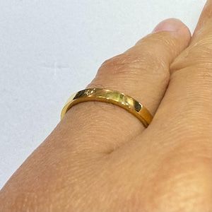 Puede incluir: Una sencilla alianza de oro con un acabado liso y pulido.