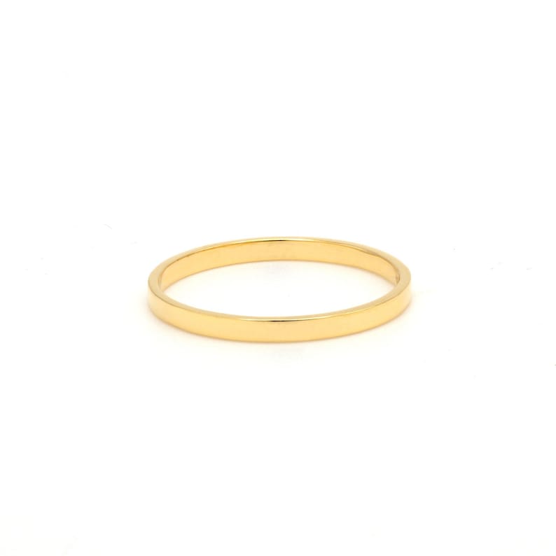 May include: A simple gold band ring.