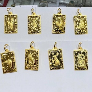 May include: Twelve gold pendants, each featuring a different Chinese zodiac animal, are displayed on a white surface. The pendants are rectangular in shape and have a detailed design.