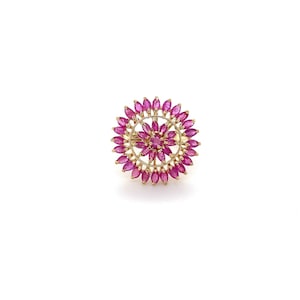 May include: A gold ring with a circular design featuring a cluster of pink ruby stones.