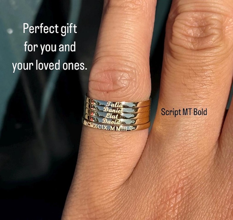 May include: A set of four gold stacking rings with the names Talia, Daniel, Liai, and David engraved on them. The rings are stacked on a finger and the font is Script MT Bold.