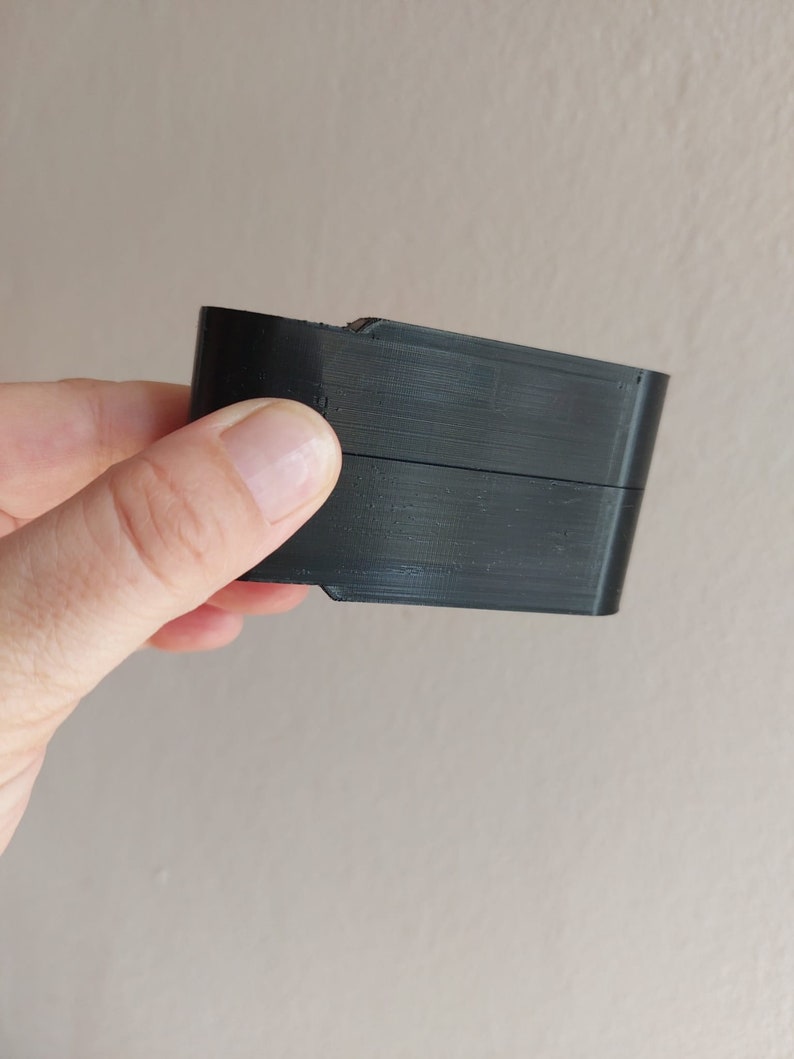 May include: A black plastic object with a rectangular shape and a slight curve on one side.