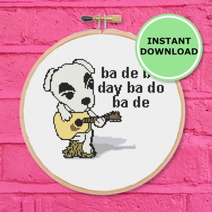 以下が含まれることがあります： 白い犬のキャラクターがギターを弾いて、「ba de ba day ba do ba de」という歌詞の曲を演奏しています。白い背景で、円形の刺繍枠に入っています。