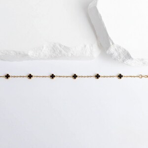 Gold Small Floral Motif Bracelet  with black clover-shaped charms on a white background