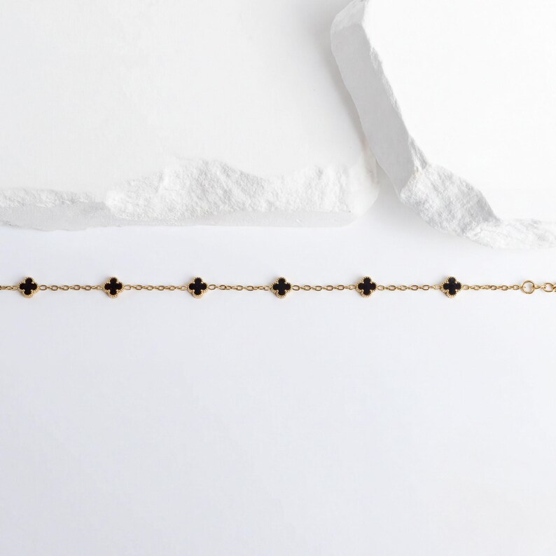 Gold Small Floral Motif Bracelet  with black clover-shaped charms on a white background