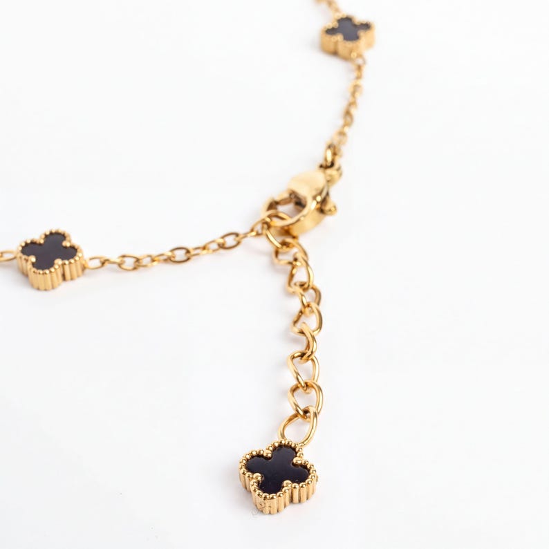 Gold Small Floral Motif Bracelet  with black clover-shaped charms on a white background