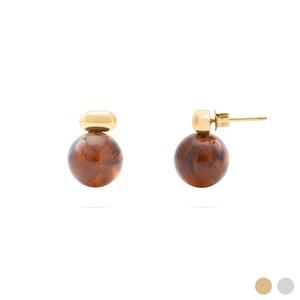 May include: A pair of stud earrings featuring a polished gold-tone metal top piece attached to a spherical, marbled brown resin bead. The earrings include a standard post and butterfly back mechanism, showcasing a smooth, glossy finish on both the metal and the resin components.