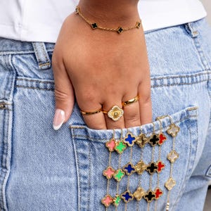 Hand with colorful floral bracelets  and rings on a denim background