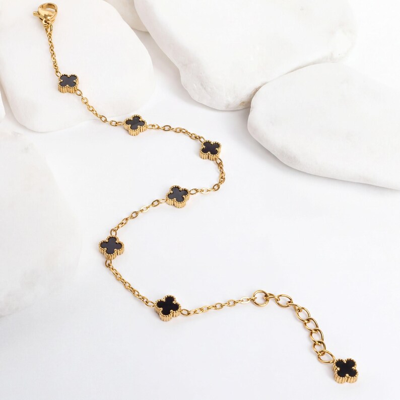 Gold Small Floral Motif Bracelet  with black flower-shaped charms on a white surface