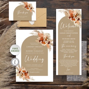 Könnte beinhalten: Eine Hochzeitseinladungssuite im Boho-Stil. Die Einladung zeigt einen braunen Bogen mit getrocknetem Pampasgras und Blumen. Der Text lautet "Gemeinsam mit ihrer Familie laden Lindsey Briant und Robert Faraday Sie herzlich zu ihrer Hochzeit ein". Die RSVP-Karte enthält eine Dankesbotschaft mit dem Text "Vielen Dank Samantha und Cristopher".