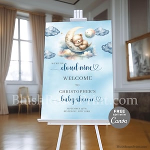 May include: A blue and white baby shower welcome sign with a cute teddy bear sleeping on a crescent moon. The sign says "We're on cloud nine" and "Welcome to Christopher's baby shower".