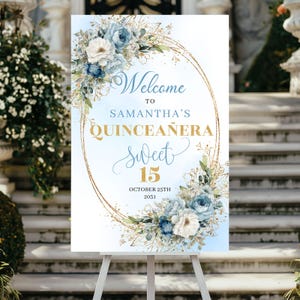 Peut inclure: Panneau de bienvenue pour une Quinceañera, avec l'inscription "Welcome to Samantha's Quinceañera Sweet 15" en lettres dorées. Décoré de compositions florales bleues et blanches et d'éléments dorés, sur un chevalet.