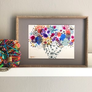 Puede incluir: Una pintura de acuarela enmarcada de un ramo de flores colorido en un jarrón. Las flores son en tonos de rosa, morado, azul, verde y amarillo. El jarrón es un diseño abstracto blanco y gris. La pintura está firmada "Ayumi".