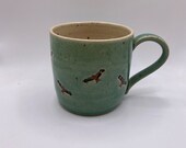 A hand thrown stoneware mug decorated with red kite birds.  A unique and charming gift.