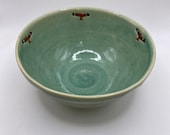 A hand thrown stoneware bowl decorated with red kite birds.  A unique item.