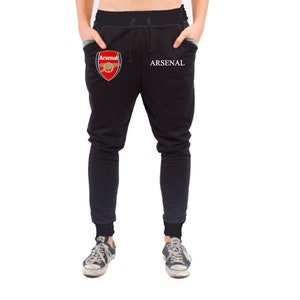 May include: Black sweatpants with a white "ARSENAL" text and a red and gold Arsenal Football Club logo on the left leg.