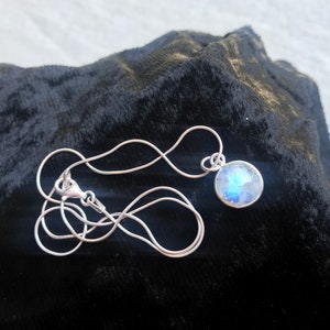 May include: A silver chain necklace with a round, iridescent moonstone pendant.