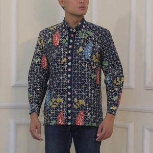 Könnte beinhalten: Ein Mann trägt ein langärmeliges, gemustertes blaues Hemd mit weißem Kragen und blaue Jeans. Er trägt weiße Turnschuhe.