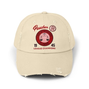 May include: A beige distressed baseball cap with a red and white logo that says "Peaches, City of Rockford, Illinois, 1945, League Champions". The logo also features a scale and a red "R" in a circle.