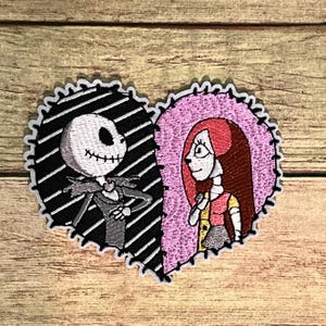 May include: Embroidered patch featuring Jack Skellington and Sally from The Nightmare Before Christmas, in a heart shape. Jack is on the left, with a black and white striped background. Sally is on the right, with a pink background. The patch has a stitched border.