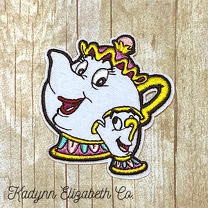 May include: Embroidered patch featuring the characters Mrs. Potts and Chip from Beauty and the Beast. The patch is white with yellow, pink, and teal accents. The text "Kadynn Elizabeth Co." is at the bottom.