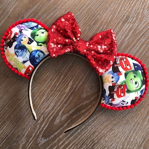 May include: Red sequin bow headband with a pair of mouse ears featuring a print of the characters from the movie Inside Out.