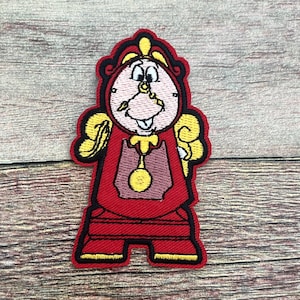 May include: Embroidered patch featuring a cartoon clock character in red, yellow, and pink. The clock has a smiling face, a pendulum, and is outlined in black. The patch is likely for clothing or accessories.