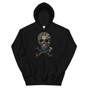 Puede incluir: Sudadera con capucha negra con un dise&ntilde;o de calavera y huesos cruzados florales. La calavera est&aacute; hecha de varias flores y hojas en tonos de rosa, amarillo, verde y azul.
