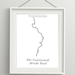 May include: A black and white line art print of the Continental Divide Trail. The print is framed in a white frame and hangs on a white wall. The text "Thruhikeboutique" and "The Continental Divide Trail" is printed below the line art.