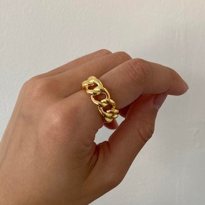 May include: A gold chunky chain ring. The ring is made of thick, linked chain metal.