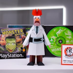 May include: A papercraft figure of Dr. Bunsen Honeydew from The Muppets, wearing a white lab coat and a black belt. The figure stands in front of a PlayStation game case and a CD case for Muppet Monster Adventure.