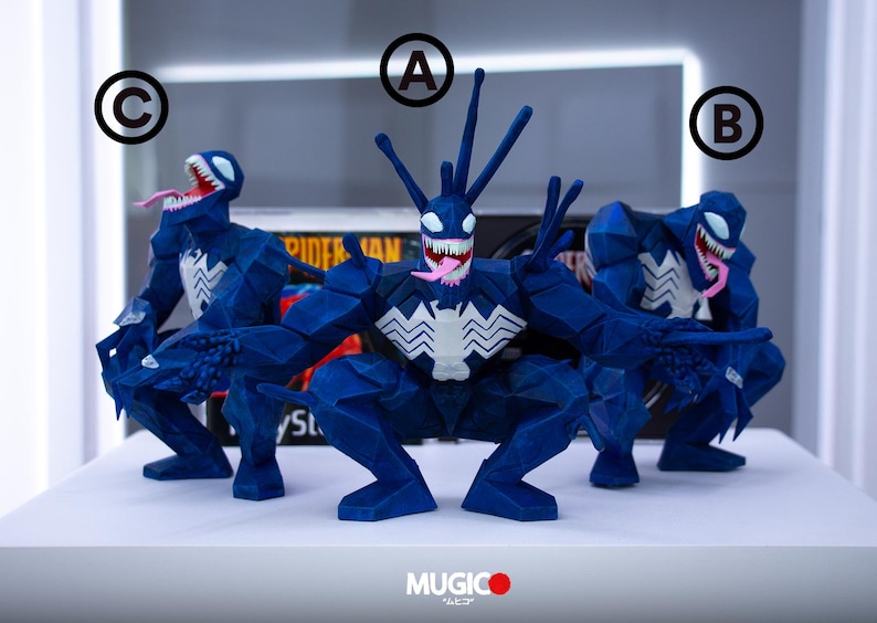 May include: Three blue Venom figures with white chest emblems and open mouths displaying pink tongues and sharp teeth. The figures are in a crouching position. The figures are on a white surface.