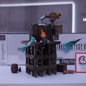 May include: A Final Fantasy VII diorama featuring two figures seated on a wooden structure with a water tap and barrels. The scene includes a PlayStation game box and a sign with Japanese text. The words "Valentine's Day Special" are also visible.