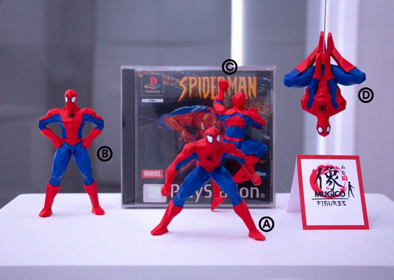 May include: A collection of Spider-Man figurines in red and blue, with a PlayStation game case in the background. One figurine is suspended upside down. A sign with Japanese text and the words "Mugico Figures" is also present.