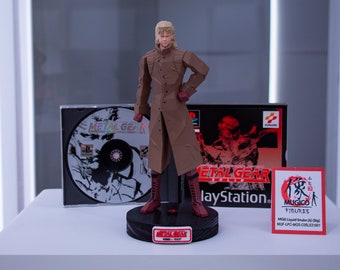 May include: A brown and red action figure of Liquid Snake from the Metal Gear Solid video game. The figure is standing on a black base with the words "Metal Gear" printed on it. The figure is holding a gun in his right hand. The figure is standing in front of a PlayStation game case for Metal Gear Solid.
