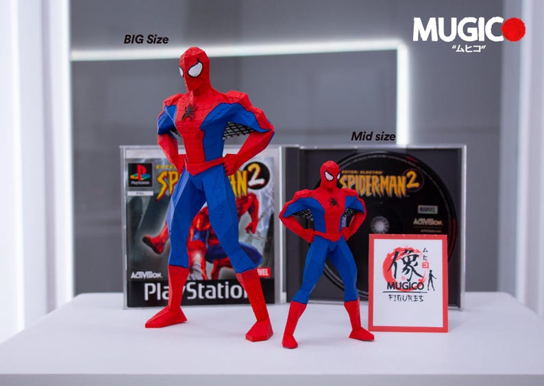 May include: Two Spider-Man action figures, one large and one mid-size, stand in front of PlayStation and DVD cases for Spider-Man 2. The figures are red and blue, with white eye masks. The text "BIG Size" and "Mid size" are visible.