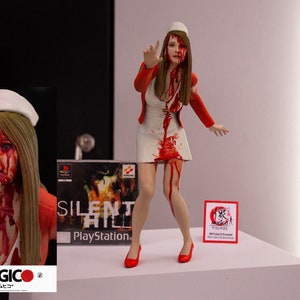 Peut inclure: Une figurine de femme en tenue d'infirmière rouge et blanche avec des éclaboussures de sang. La figurine lève une main en l'air. La figurine est debout sur une surface blanche. La figurine est issue de la série de jeux vidéo Silent Hill.