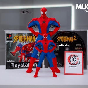 May include: Two Spider-Man action figures, one large and one mid-size, stand in front of PlayStation game cases. The figures are red and blue, with the text "BIG Size" and "Mid size" visible. A small sign reads "MUGICO FIGURES."
