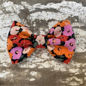 May include: A floral bow tie with a black background and orange, pink, and red flowers.