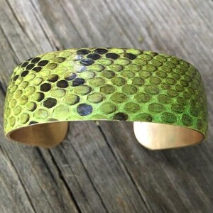 Pu&ograve; includere: Un braccialetto in pelle di serpente verde con una fascia in ottone. Il braccialetto &egrave; realizzato in vera pelle di serpente e presenta un motivo unico.