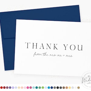 May include: A white thank you card with black text that reads "THANK YOU from the new mr + mrs". The card is sitting on top of a navy blue envelope.