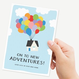 Puede incluir: Una tarjeta azul claro con una ilustraci&oacute;n de dibujos animados de una casa flotando en el aire con globos de colores. El texto en la tarjeta dice "On to new adventures! Good luck in your new home."