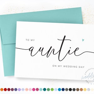 May include: A white greeting card with black cursive text that reads TO MY auntie ON MY WEDDING DAY, featuring a small light blue heart icon. The card is paired with a matching light blue envelope, all presented against a white background.