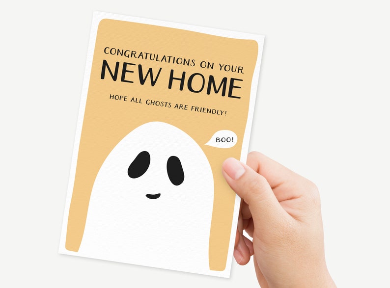 May include: A light orange card with the text "Congratulations on your new home. Hope all ghosts are friendly!" and a white ghost with black eyes and a mouth saying "Boo!"