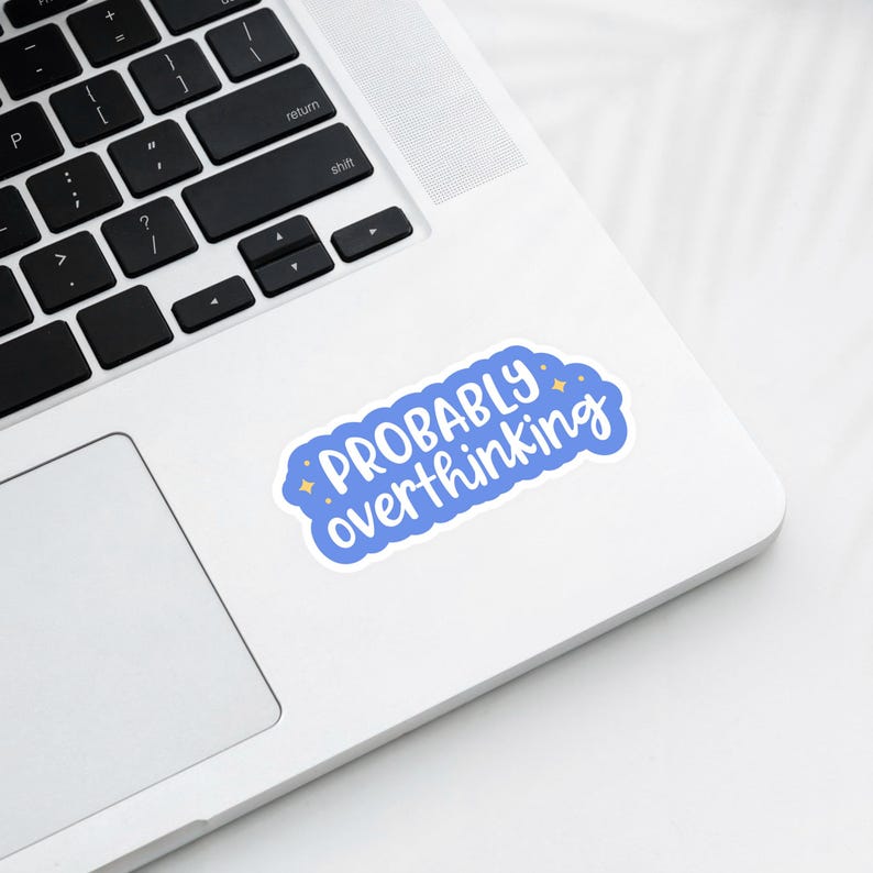 Puede incluir: Una pegatina con la frase "PROBABLY overthinking" en blanco sobre un fondo azul en forma de nube. La pegatina est&aacute; colocada sobre un ordenador port&aacute;til blanco.