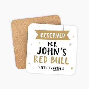 May include: White coaster with gold and silver stars and the text "RESERVED FOR JOHN'S RED BULL (REFILL AS NEEDED)"